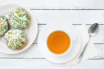 White cup of green tea and cake shu on plate wooden background