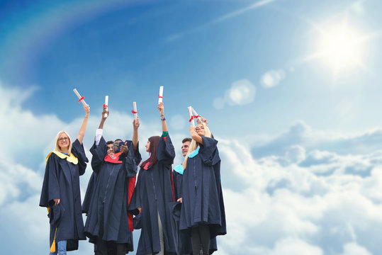 education, graduation and people concept - silhouettes of many happy students in gowns throwing mortarboards in air
