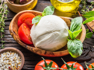 Buffalo mozzarella in the wooden bowl on the table. Food background.