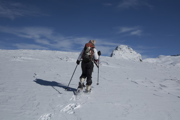 Fototapeta na wymiar Mujer joven con raquetas de nieve paseando en alta montaña