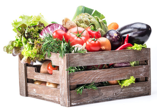 Fresh multi-colored vegetables in wooden crate.