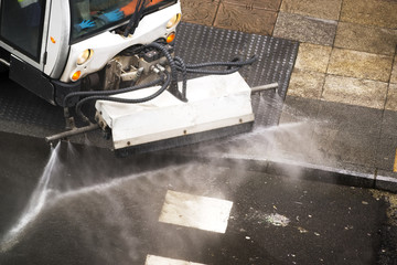 sweeper gardener  cleaning  the city street with pressure water