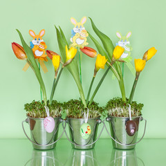 Easter decoration in metal buckets on a green background.