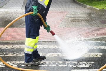 sweeper gardener  cleaning  the city street with pressure water