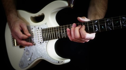 A man plays solo on a white electric guitar on a black background - 2.