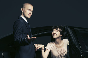Happy young fashion couple with a car in night