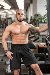 Fototapeta na wymiar Young handsome sporty muscular man posing in gym