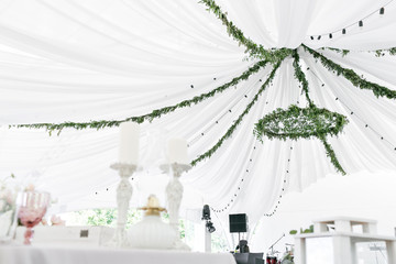 Chandelier made of green leaves and branches hangs under the light tent. decorative lights. Nature style