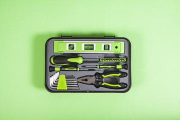 Mix of different tools in one box on green background