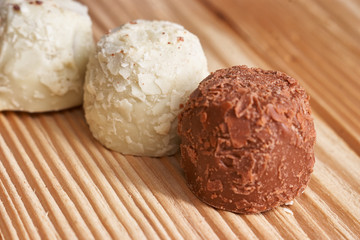 Macro. White and milk chocolate candies on a light wooden background