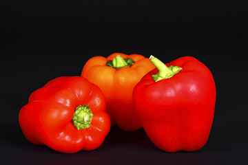 Three ripe red peppers isolated on a black background