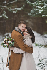 The newlyweds hug each other against the background of the winter fore