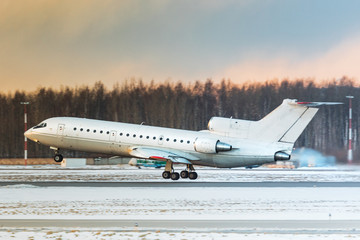 Regional passenger airplane taking off at sunset, side view, sunset sky on background. Aviation...
