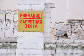 Placard with an inscription in Russian "Attention! Forbidden Zone" on a brick wall