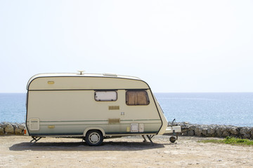 Caravan on the sand beach with the blue sea on background