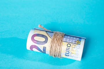 the Twenty Euro notes rolled over a blue background