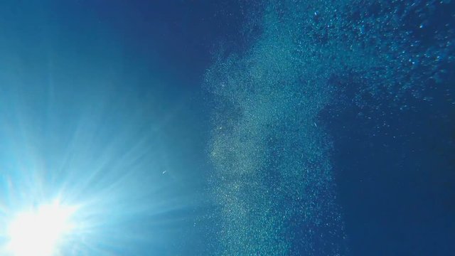 Man diving in swimming pool, sea or ocean underwater view. Swimmer jumping in to the water. Wave and sun underwater over blue sunny sky background. Shot with GOPRO HERO4 4K UHD video.