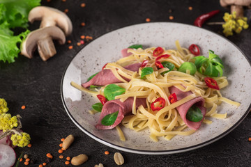 Italian spaghetti. Tagliatelle pasta with ham. Selective focus. Black background. Top view