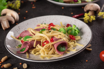 Italian spaghetti. Tagliatelle pasta with ham. Selective focus. Black background. Top view