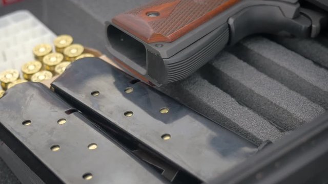 Handgun with loaded clips and ammo in slow motion. The handheld shot of the pistol and bullets represents America's political debate between its schoolchildren and the NRA, gun control & social issues
