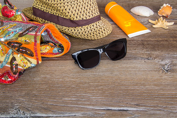 Summer sea background - seashells, sunscreen, beach hat, beach bag, sunglasses, on a wooden...