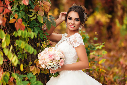 Portrait of a smiling bride in a colorful autumn forest