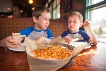 kids eating pizza at cafe. children eat unhealthy food indoors. selective focus © EvgeniiAnd