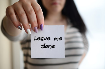 Young sad girl shows a white sticker. Caucasian brunette holding a sheet of paper with message....