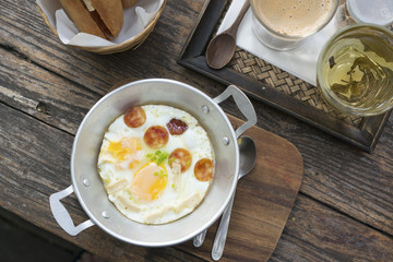 Breakfast set, Bread, hot coffee, egg omelette and hot tea on wood table, natural light.