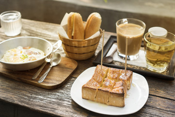 Breakfast set, Bread, hot coffee, egg omelette and hot tea on wood table, natural light.