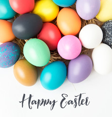 Multi-colored Easter eggs in nest on wooden background, selective focus image. Happy Easter card 