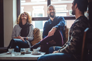 Friends laughing in a cafe while drinking coffee