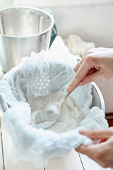 woman preparing vegan almond or coconut milk at home. Pouring the milk into a cheese cloth to...
