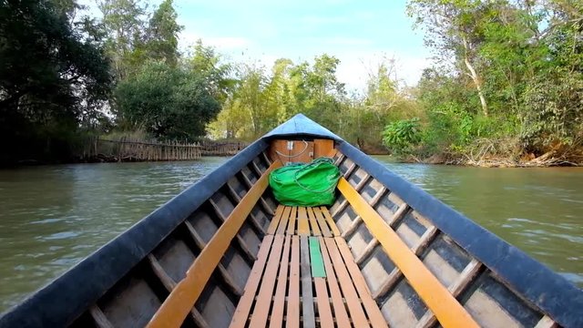 Canoe boat sails along the Inn Thein (Inn Dein, Indein) creek of Inle Lake with a view on forests and agricultural lands on the banks, Myanmar.