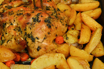 Baked in the oven chicken with potatoes, carrots, herbs and spices.