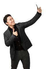 Smiling happy man taking a selfie with his phone and doing thumbs up. White background.