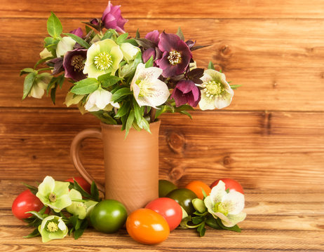 Rustic Easter still life. Easter eggs, blossoms Hellebore flowers in rustic jug.
