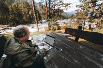 Adult man entrepreneur is sitting outdoors at the table of a mountain tourist resort during his...