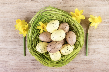 Easter nest filled with yellow and brown pastel Easter Eggs. Top view, close-up.