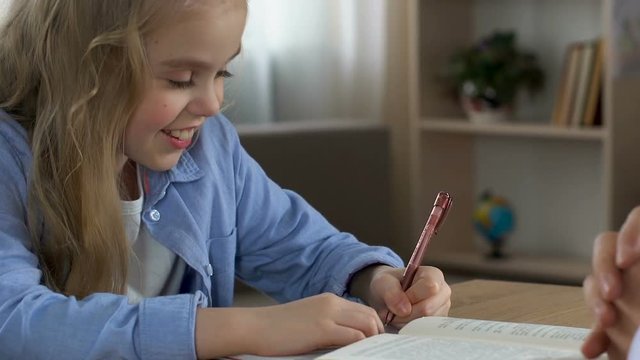 Little girl learning to write and proud father stroking head, love and support