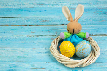 Happy Easter.Colorful shiny eggs and rabbit on wooden table background. wreath woven from the vines. Copy space for text. Top view.
