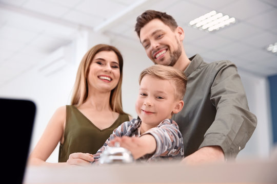 Family ringing service bell on reception desk in hotel