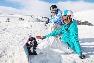 Fototapeta na wymiar Couple of snowboarders on ski piste at snowy resort. Winter vacation