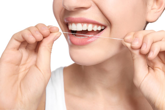 Young woman flossing her teeth on white background, closeup