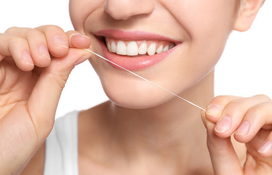 Young woman flossing her teeth on white background, closeup