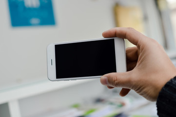 Close up on hand using mobile phone with blank copyspace display for advertising text message or content mockup background. Professional payment technology, game playing, video filming or photography