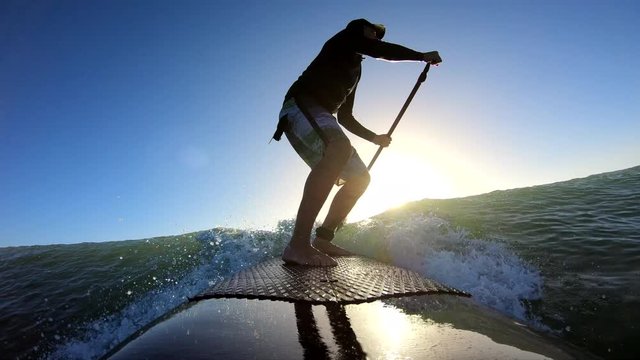 Standup paddle board surfing a wave at sunrise point of view, New Zealand