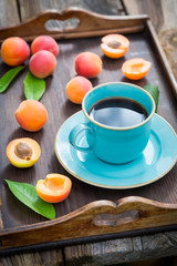 Fresh coffee and plums on wooden tray