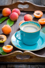 Delicious coffee and plums on wooden tray