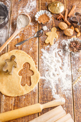 The process of making classic ginger biscuits in the form of little men. Still life on a wooden background with ingredients and figurines.